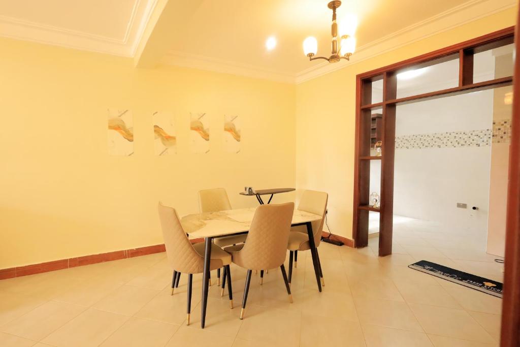 een eetkamer met een tafel en stoelen bij Homes by her in Entebbe