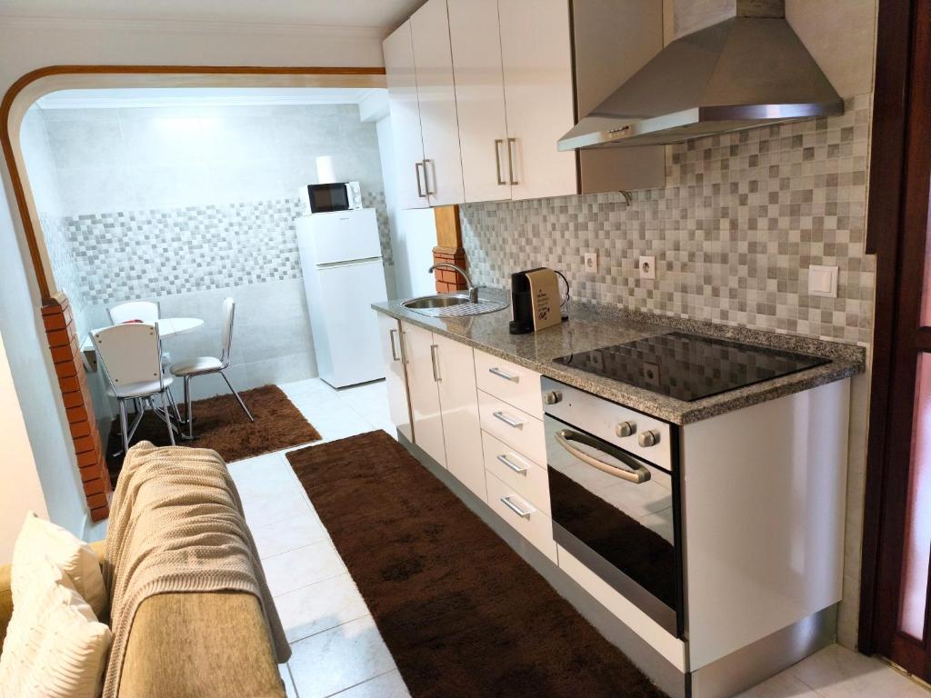 een keuken met een fornuis top oven naast een bank bij ManelMar O Refúgio in Nazaré