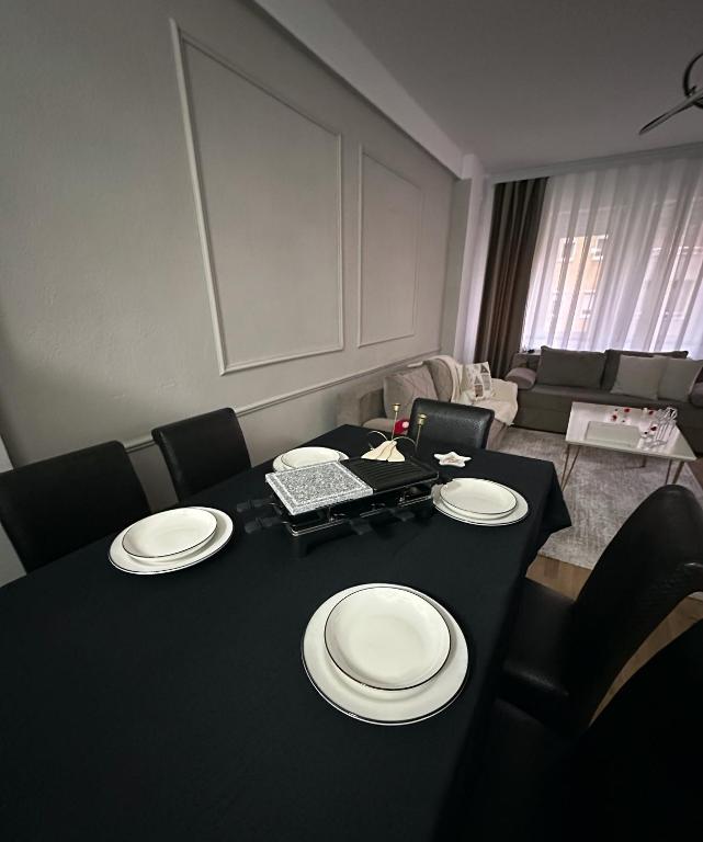 una sala da pranzo con un tavolo nero con sopra piatti bianchi di 01 Apartment a Kosovo Polje