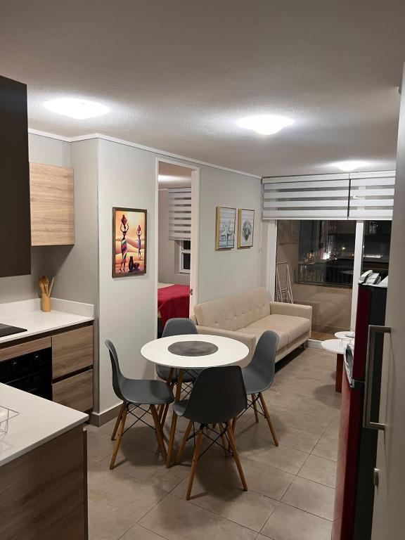 een keuken en een woonkamer met een tafel en stoelen bij Departamento claro solar in Temuco