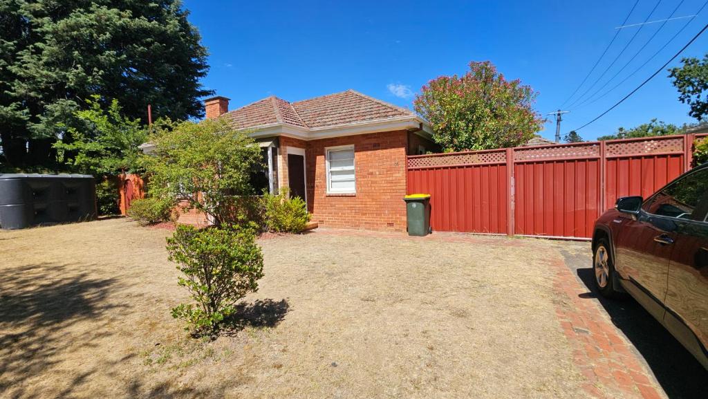 une maison en briques rouges avec une clôture rouge dans l'établissement Griffin lakeside, à Yarralumla