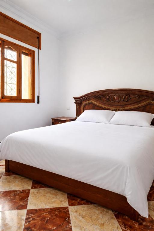a bedroom with a large bed with a wooden headboard at Villa abdo in Asilah