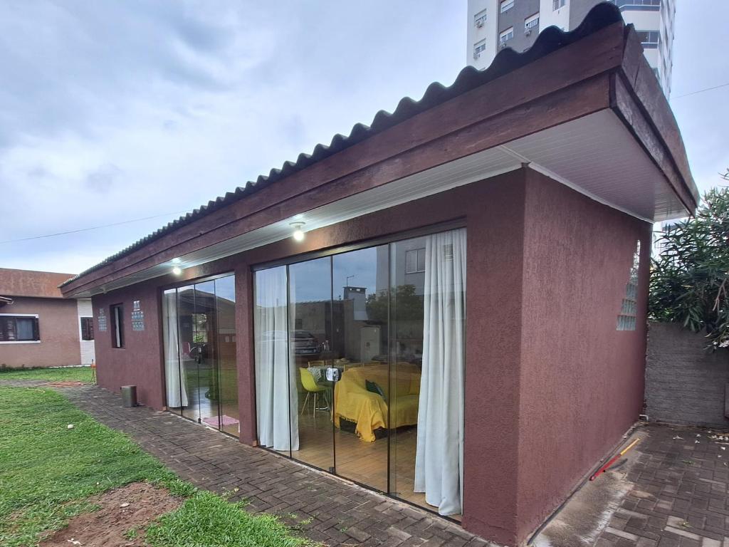 een huis met glazen schuifdeuren en een tafel bij Espaço artemísia in Tramandaí