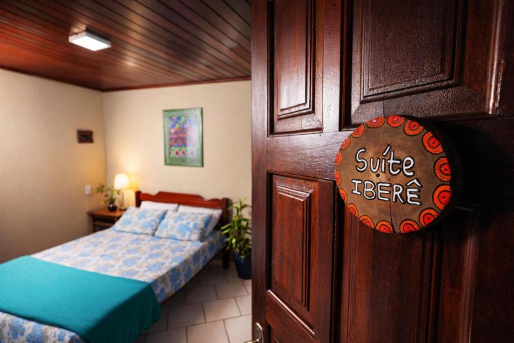 - une chambre avec un lit et un panneau sur une porte dans l'établissement Suíte Iberê - Pousada Jussara, à Joinville