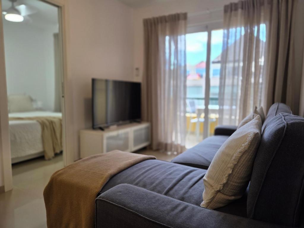 a living room with a blue couch and a television at Oliva Home in Los Cristianos