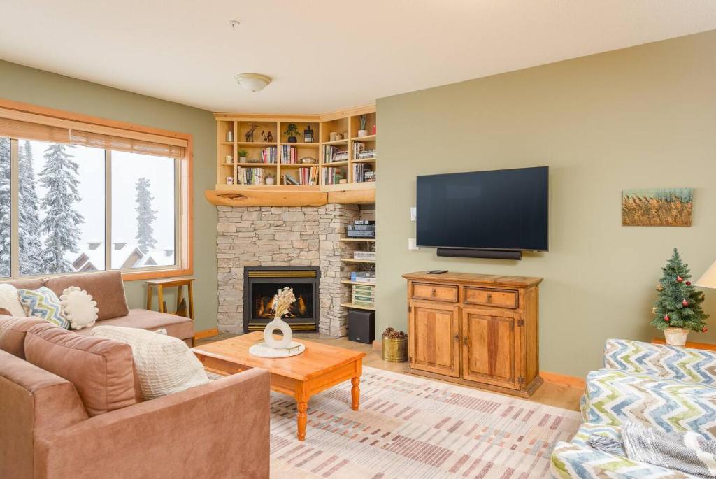 a living room with a tv and a fireplace at Snowy Creek Chalet in Big White