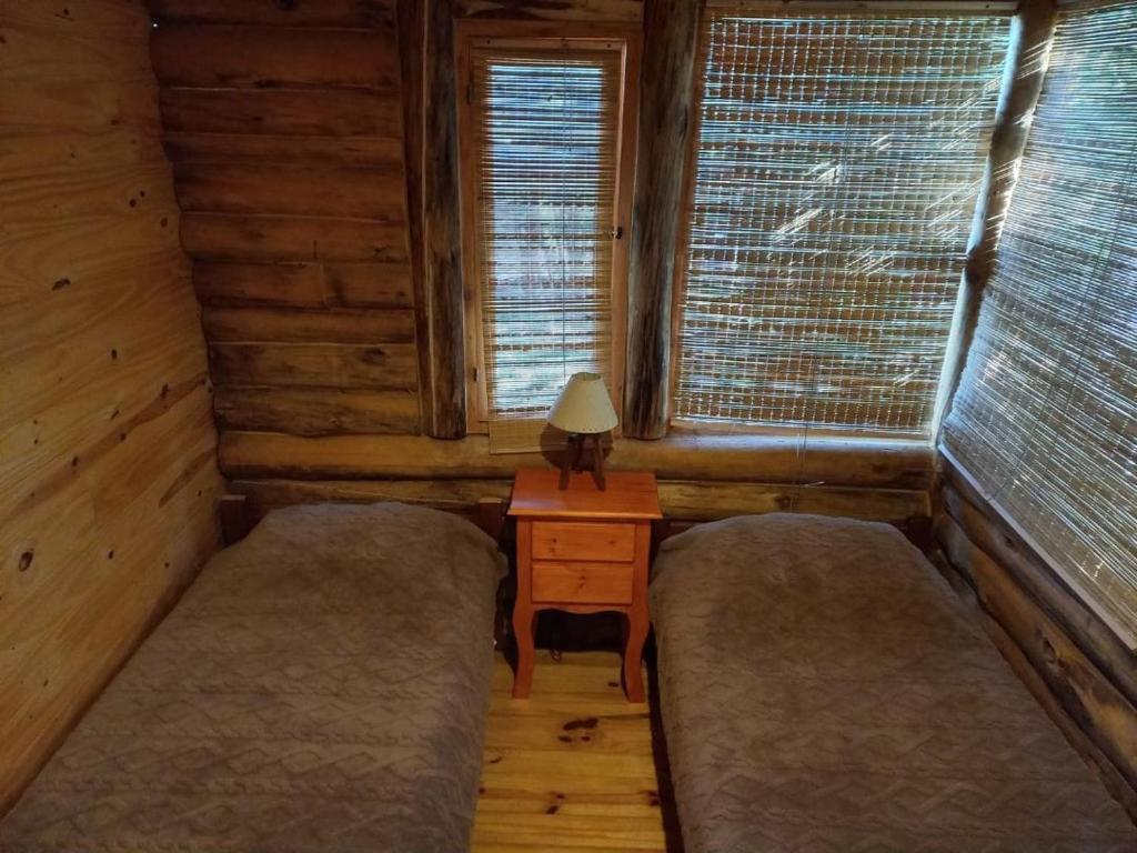 een kamer met 2 bedden, een tafel en 2 ramen bij Los Lirios in Villa Giardino