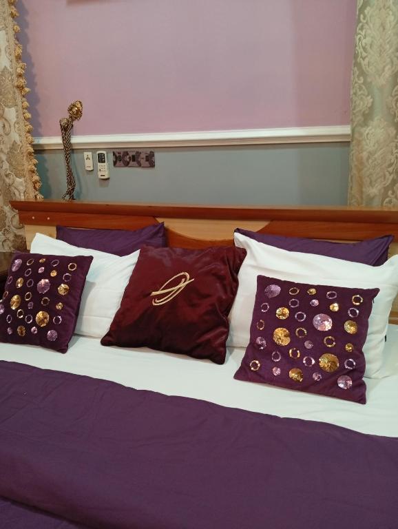a bed with purple and white pillows on it at Andweruth Residences in Abuja