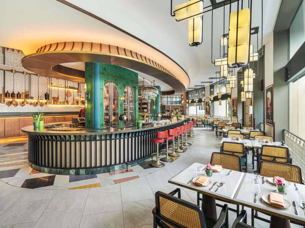 ein Restaurant mit Tischen und Stühlen und eine Bar in der Unterkunft Fairmont Singapore in Singapur