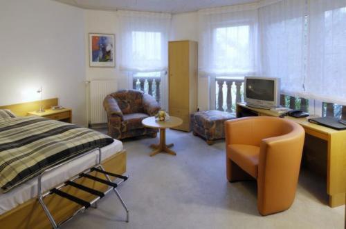 1 dormitorio con cama, escritorio y silla en Landgasthaus Hotel H. Kortlüke, en Belm