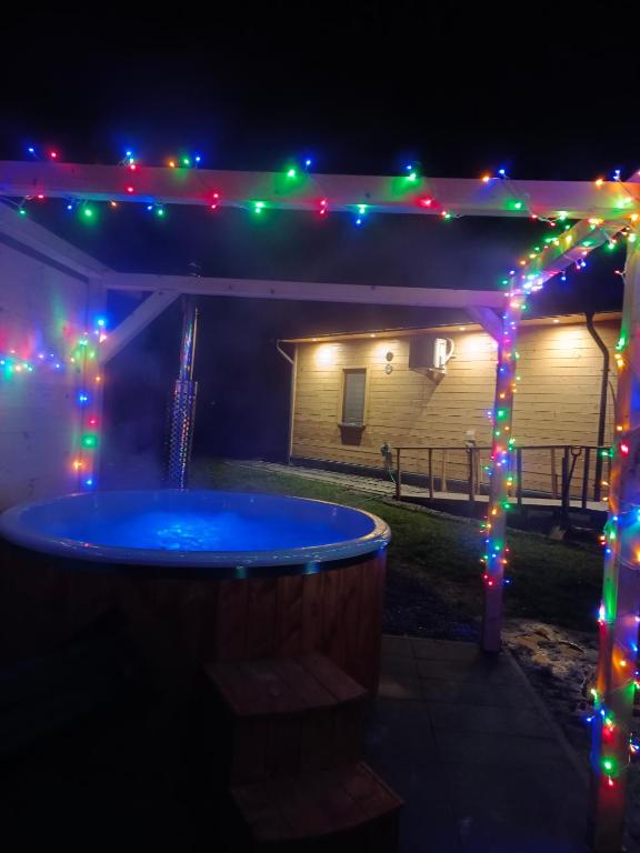 a lit up hot tub under a pergola with christmas lights at Aura Roztocze - Domek z balią przy lesie in Zamość