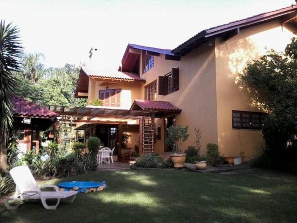 ein Haus mit einem Garten mit Stühlen und einem Tisch in der Unterkunft Casa das Palmeiras + Quiosque in Bento Gonçalves