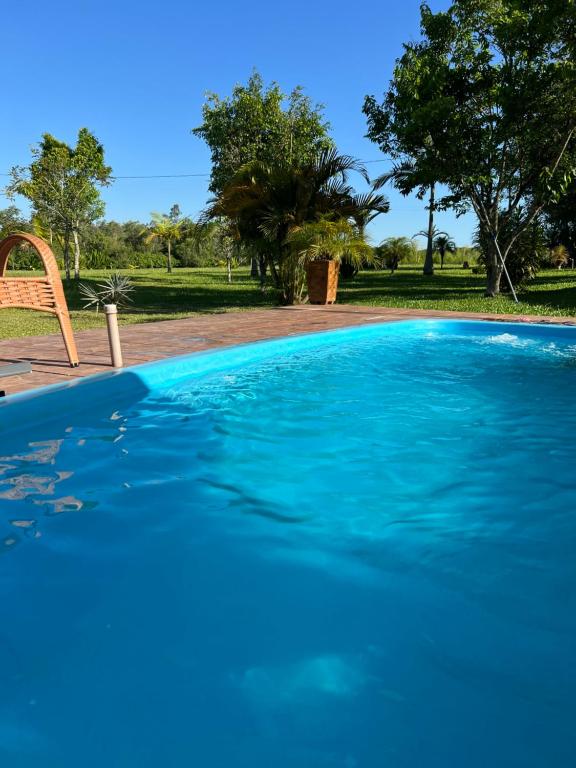 een groot blauw zwembad met bomen op de achtergrond bij Chacara do japonês 