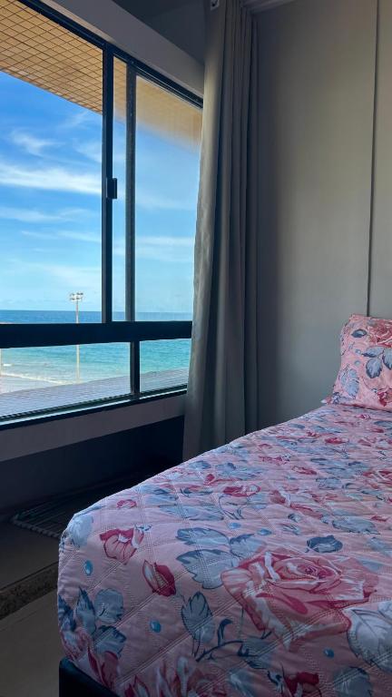 a bedroom with a bed with a view of the ocean at Farol da Barra 209 in Salvador