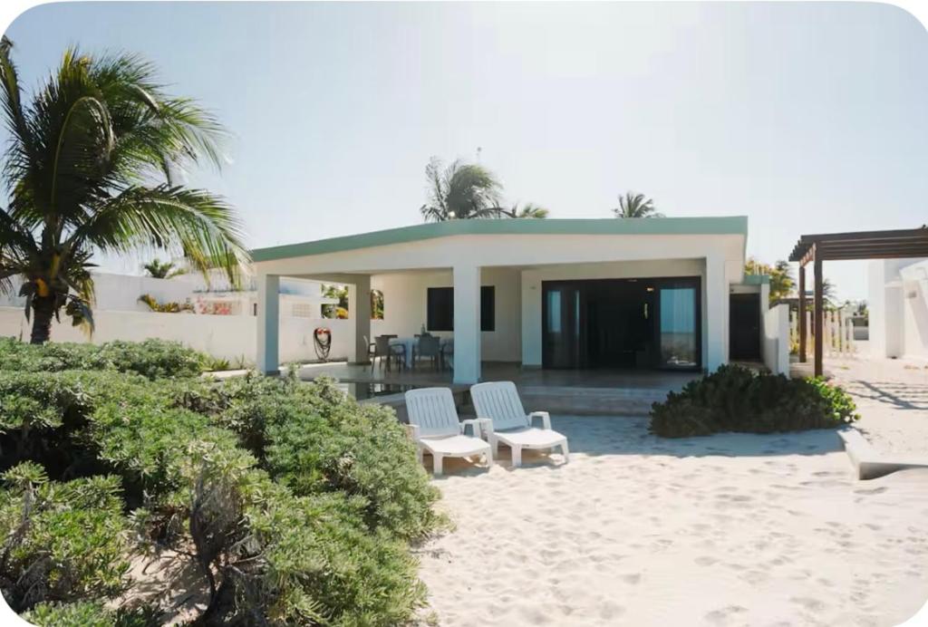 ein Haus am Strand mit zwei Stühlen und einer Veranda in der Unterkunft Beach house Chuchos in Chelem