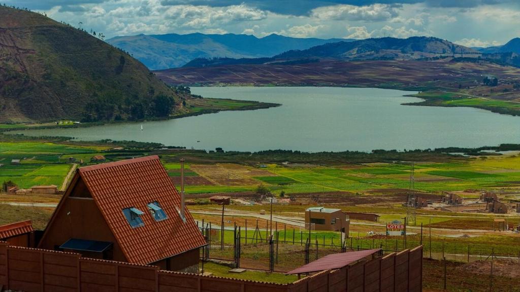 a view of a lake and a house next to a fence at Cabaña mágica en Valle Sagrado in Cusco