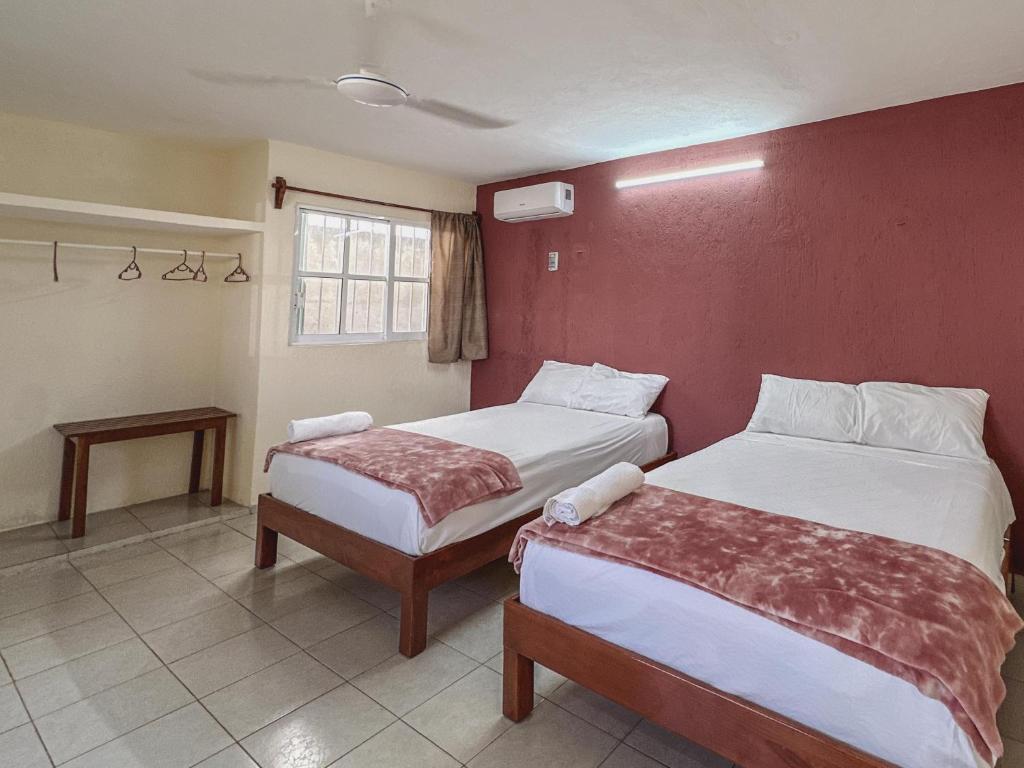 een slaapkamer met 2 bedden en een rode muur bij Sol y Luna Hospedaje in Valladolid