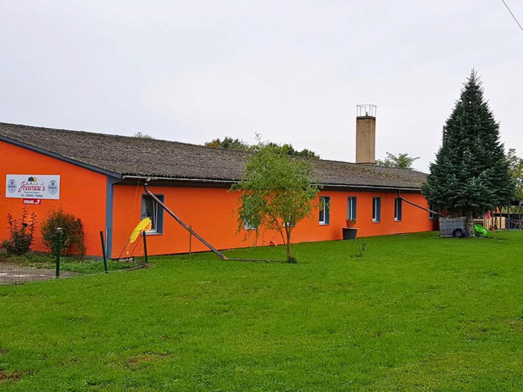 ein orangefarbenes Gebäude mit einem Baum davor in der Unterkunft Family-Friendly Guesthouse in the Oderbruch in Genschmar