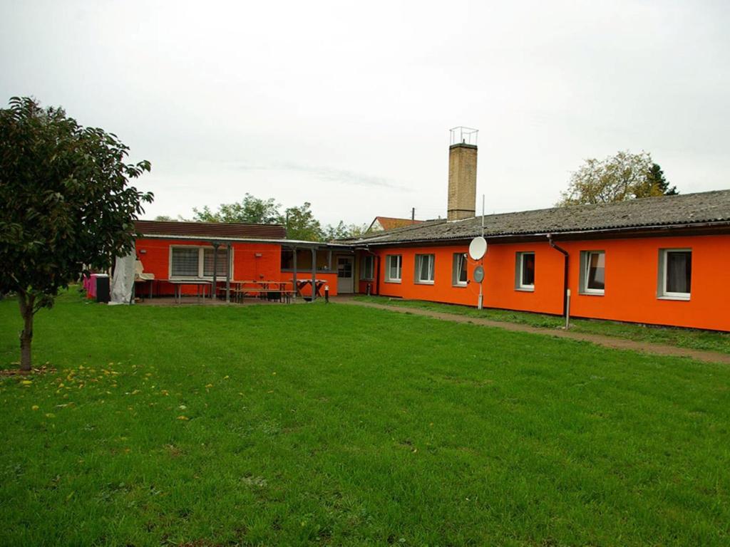 ein orangenes Haus mit grünem Rasen davor in der Unterkunft Family-Friendly Guesthouse in the Oderbruch in Genschmar