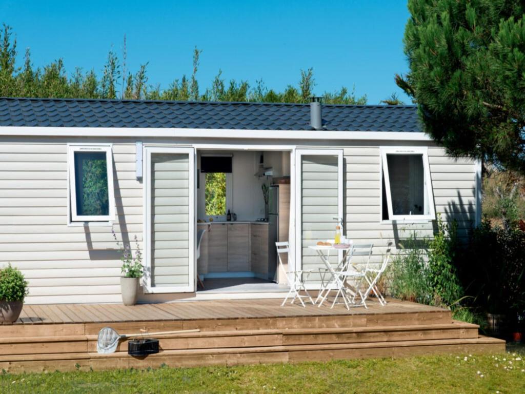 a small white caravan with a wooden deck at 6-Guest Escape with Private Garden & Wi-Fi in Overbroek