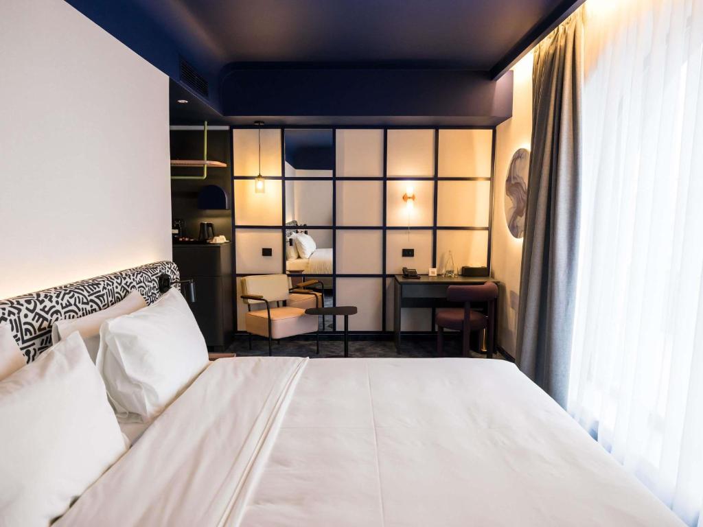 a bedroom with a white bed and a desk at Mercure Bucharest Cantemir in Bucharest