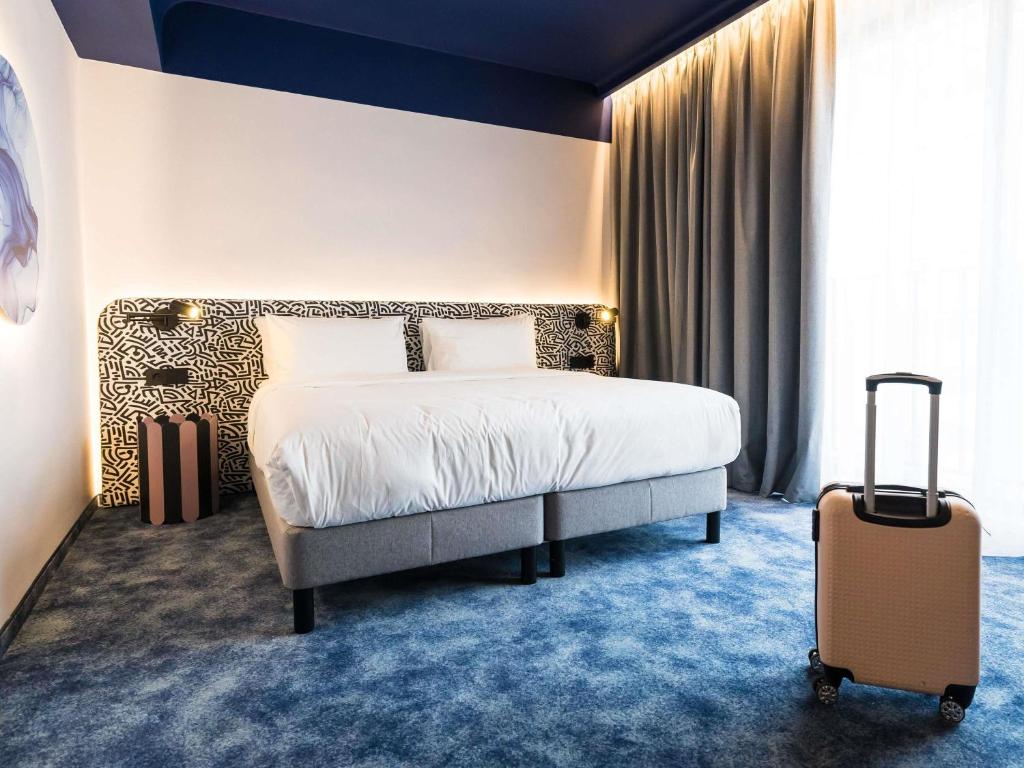 een hotelkamer met een bed en een koffer bij Mercure Bucharest Cantemir in Boekarest