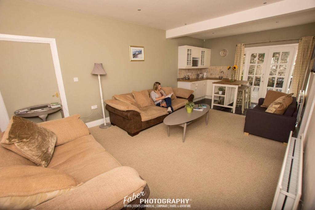 a woman sitting on a couch in a living room at The Castle Apartment in Strangford