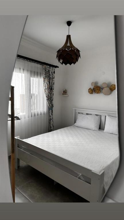 a large bed in a bedroom with a chandelier at Yasemin Pansiyon Plus in Seferihisar
