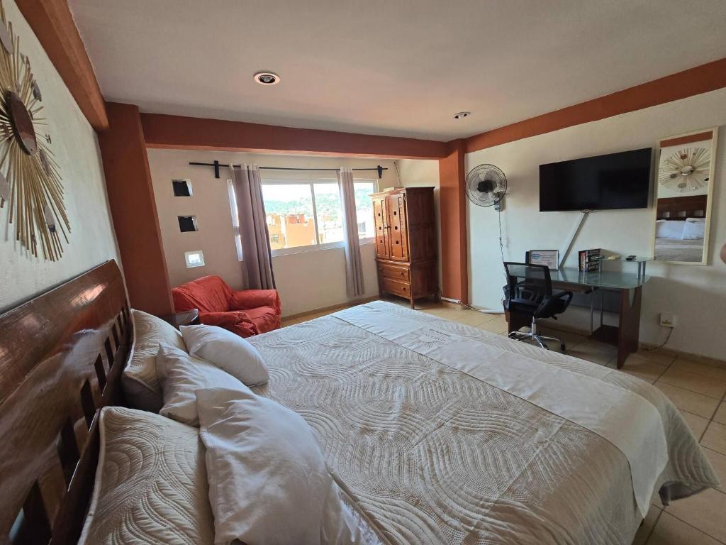 a bedroom with a large bed and a desk at Loft Rayito de Sol, Zihuatanejo Center with AC in Zihuatanejo