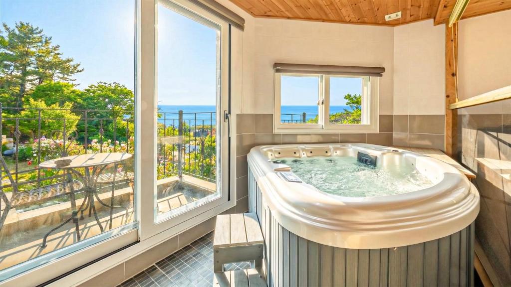 einen Whirlpool in einem Zimmer mit einem großen Fenster in der Unterkunft Ganghwa Hanabi Pension in Incheon