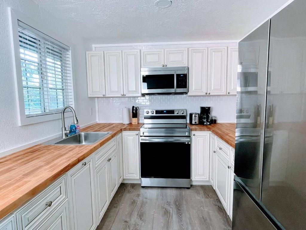 a kitchen with white cabinets and a black refrigerator at The Sitka Spruce House in Forks