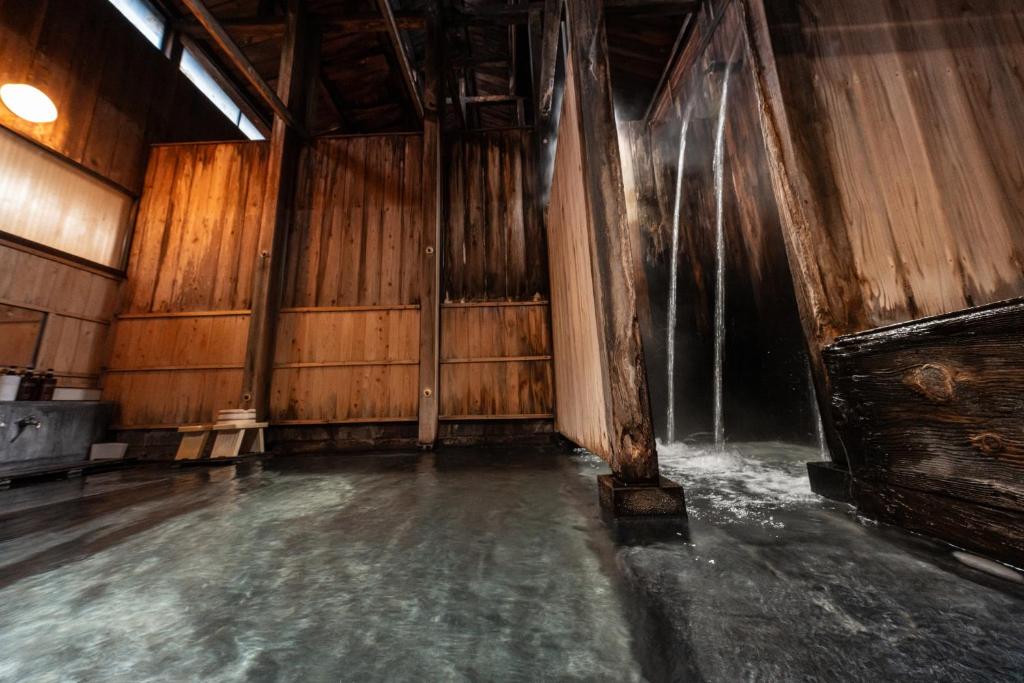 an empty room with a waterfall in a wooden building at ShirabuOnsen Higashiya in Yonezawa