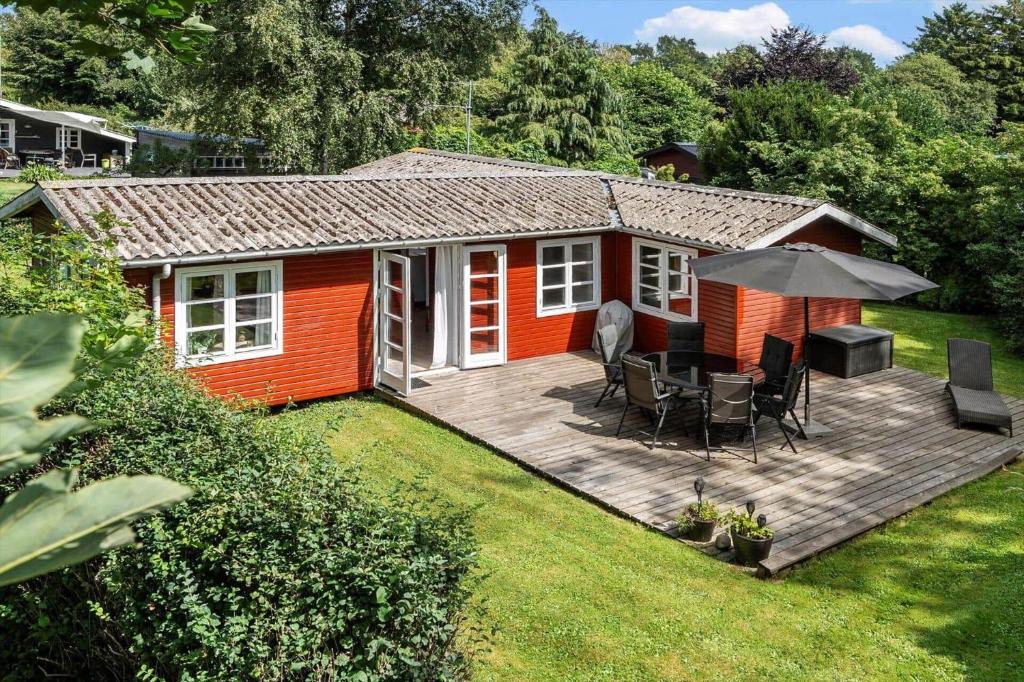 una piccola casa rossa con un ponte e un ombrellone di 3032-Stege-Ankeret-4 a Stege