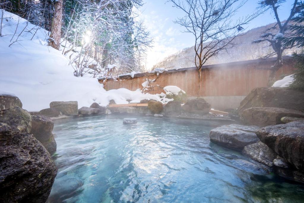 a pool of water with snow on the ground at ShirabuOnsen Higashiya in Yonezawa