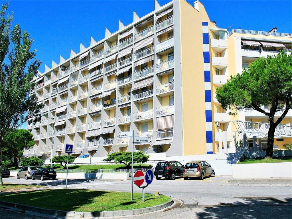 a large building with cars parked in a parking lot at Caorle Holiday Home with Terrace in Porto Santa Margherita di Caorle