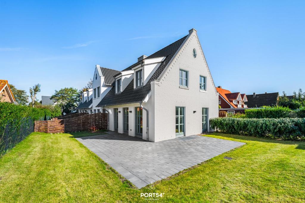 een wit huis met een zwart dak en een tuin bij Villa Tinnum Sylt in Tinnum