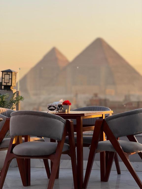 a table and chairs with pyramids in the background at NEW ASSER HOTEL PYRAMID in Cairo
