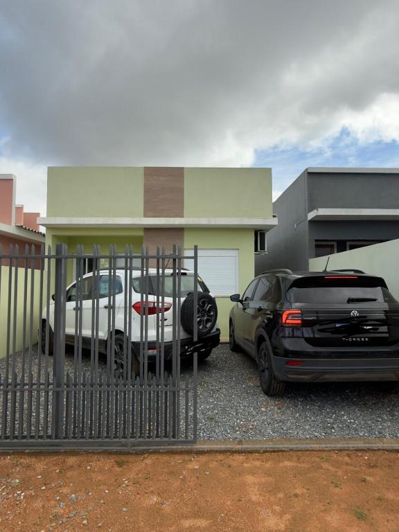 two cars parked in front of a house at Casa Verde próxima a BR 290 in São Gabriel