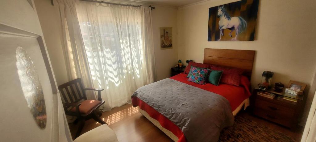 a bedroom with a bed with a red blanket and a window at Viña acogedor lugar a pasos del reloj de flores in Viña del Mar