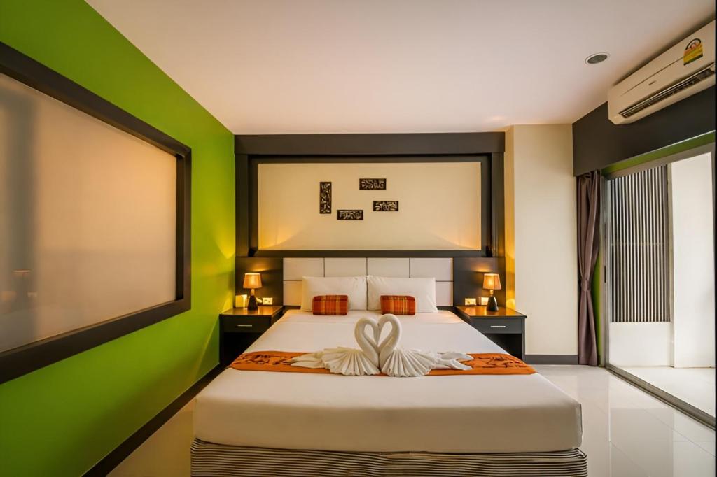 a bedroom with a large bed with green walls at Star House Patong in Patong Beach