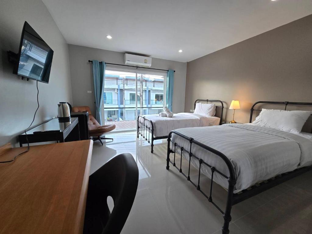 een slaapkamer met 2 bedden, een bureau en een televisie bij Khao Oat airport in Nai Yang Beach