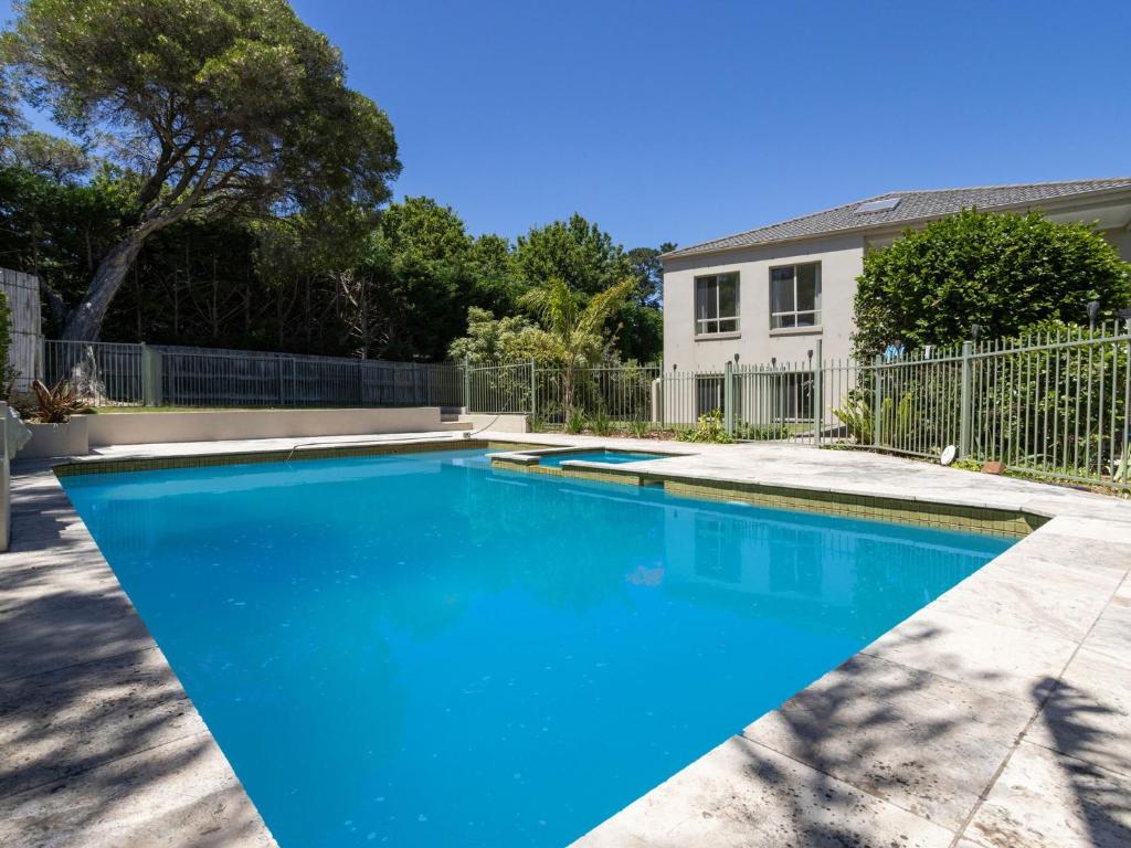 une piscine avec de l'eau bleue devant une maison dans l'établissement Jacksons Coast House, à Mount Eliza