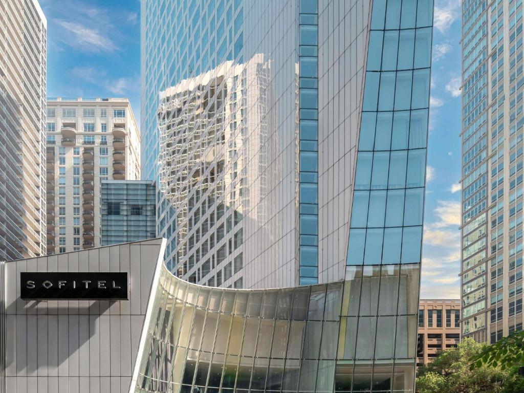 ein großes Glasgebäude in einer Stadt mit hohen Gebäuden in der Unterkunft Sofitel Chicago Magnificent Mile in Chicago