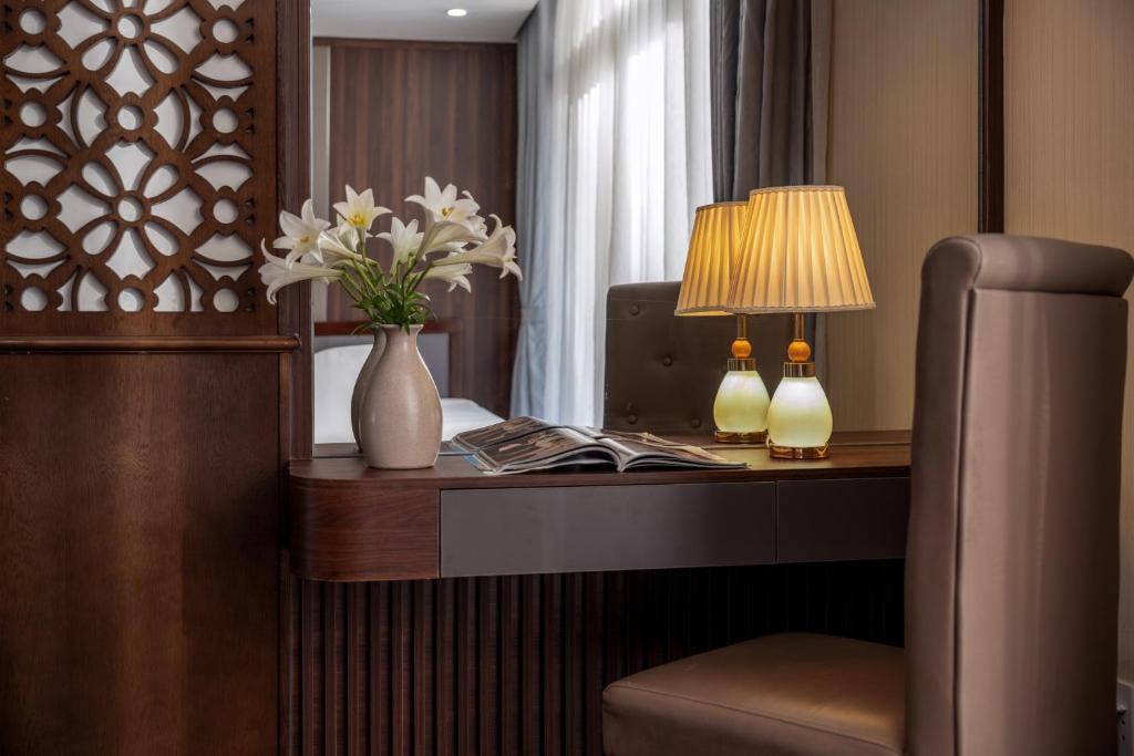 A compact writing desk styled with a lamp, flowers, and reading material.