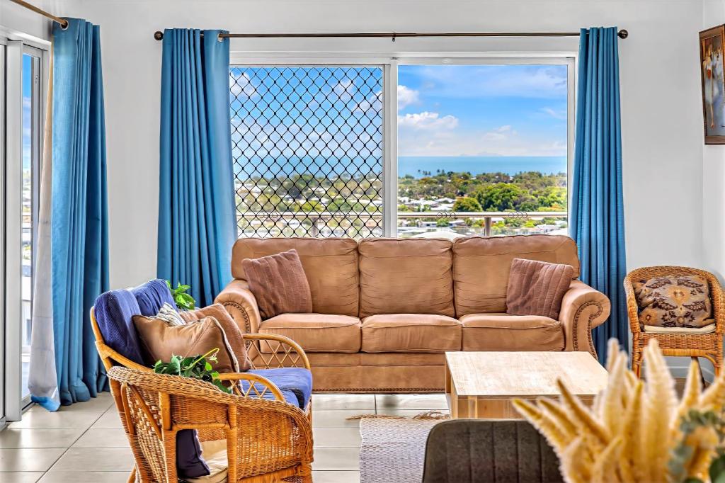 un soggiorno con divano, sedie e una grande finestra di Panoramic Oceanview Villa a Bowen