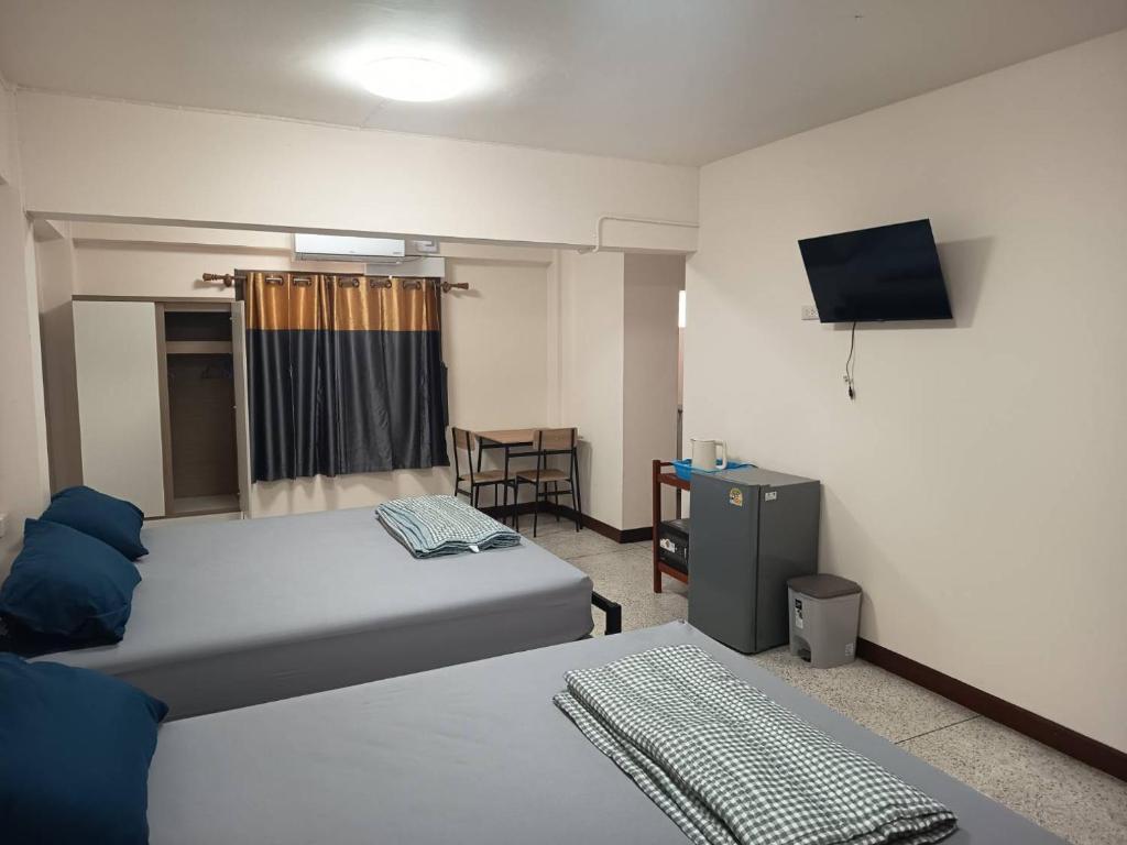 una camera d'albergo con due letti e una televisione di Doctor Thanut Hostel a Ubon Ratchathani