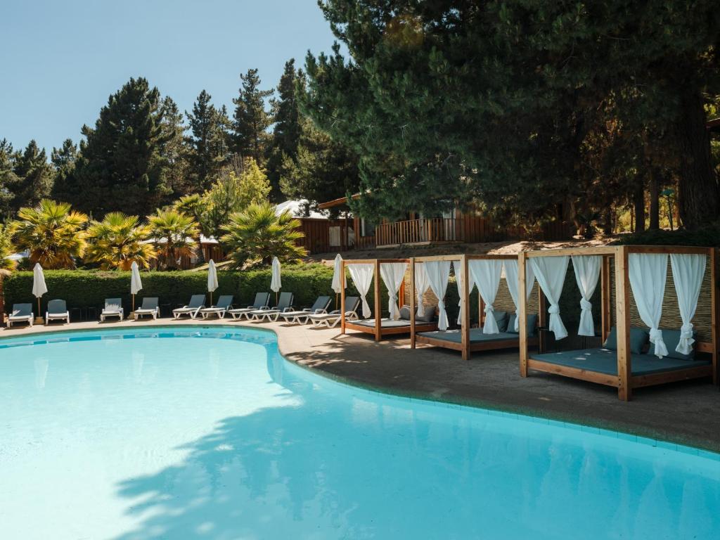 a swimming pool with chairs and umbrellas next to at Pao Pao Lodge Algarrobo in Algarrobo