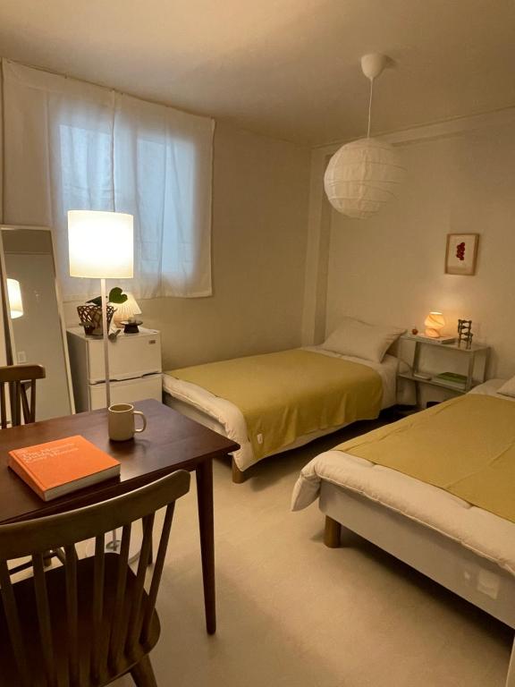 een kamer met twee bedden, een tafel en een bureau bij Stay early mansion in Incheon