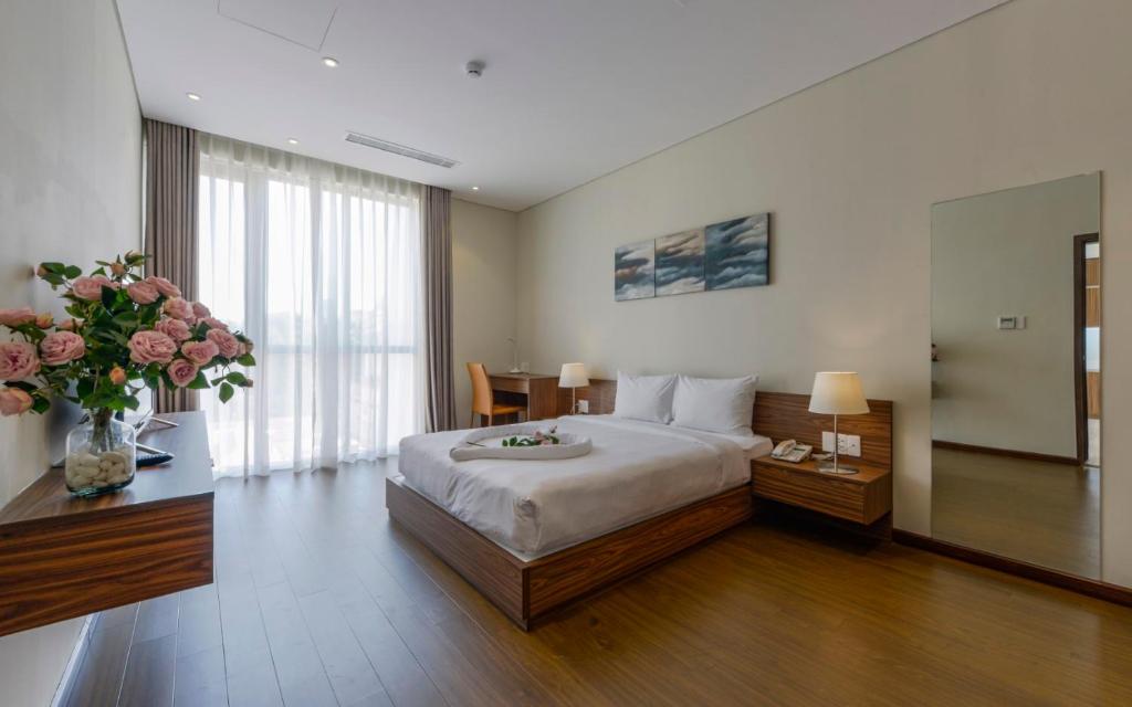 a hotel room with a bed and a table with flowers at Aurora Serviced Apartments in Ho Chi Minh City