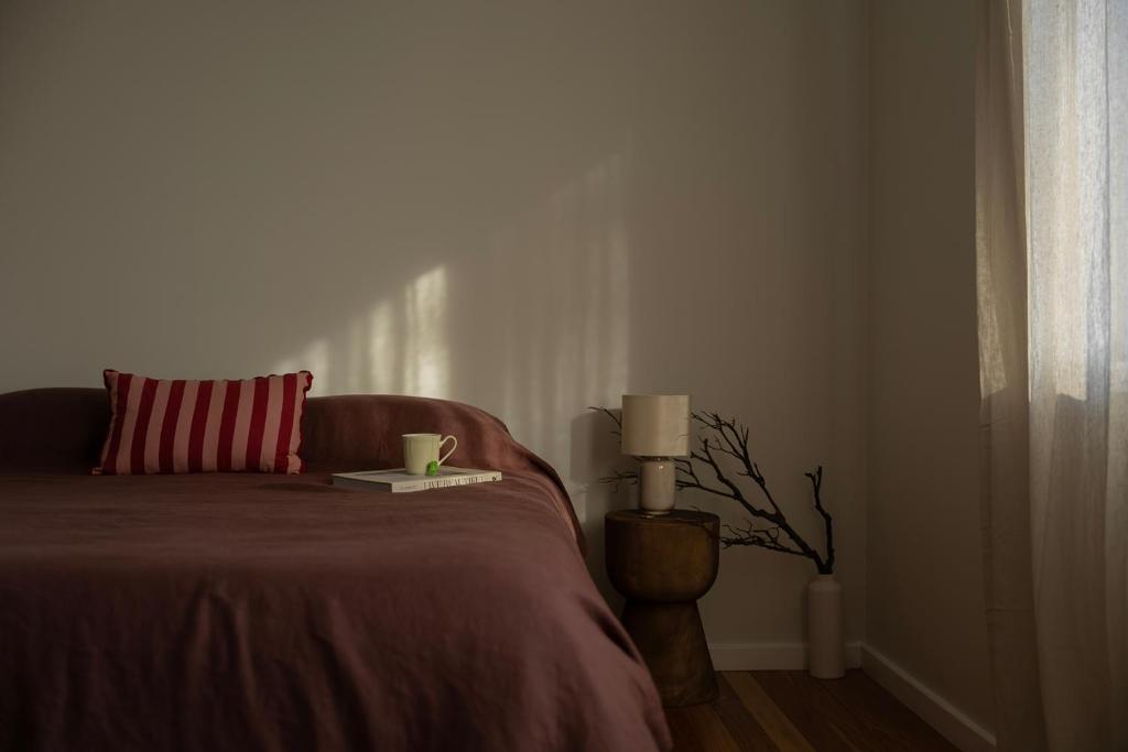 a bedroom with a bed with a book and a cup on it at La Costa Shoal Bay in Shoal Bay